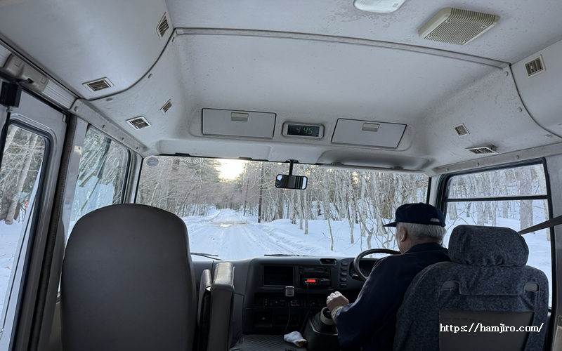 雪の林道を進む送迎バス