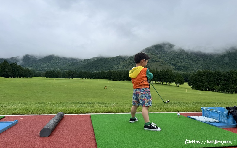 ゴルフ練習場での子供のスイング